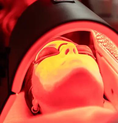 Kunde liegt mit dem Gesicht unter einer Rotlichtlampe